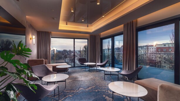 A modern hotel room with large windows, comfortable seating, and a city view. - My Story Gdynia (Gdynia)