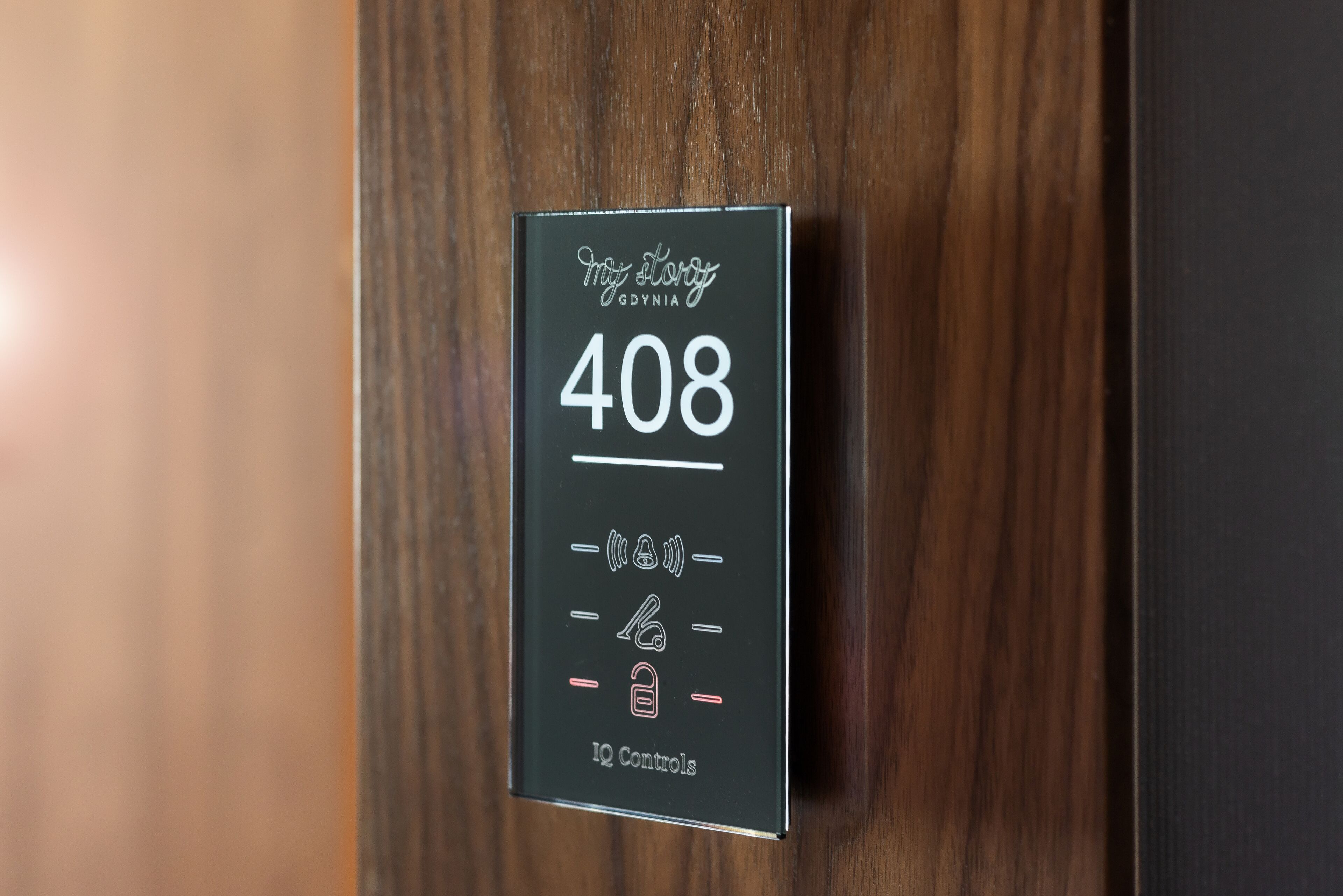Un panel digital negro sobre una puerta de madera con el texto "My Story GDYNA 408 IQ Controls".