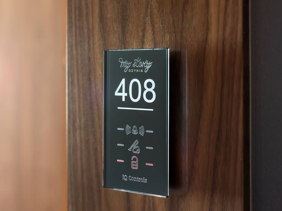Un panel digital negro sobre una puerta de madera con el texto "My Story GDYNA 408 IQ Controls".