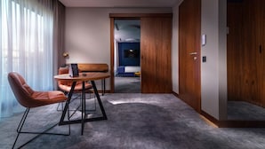 A modern hotel room with a round table, two leather chairs, a bed, and a TV. - My Story Gdynia (Gdynia)