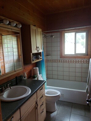 Bañera con ducha, toallas, jabón, shampoo