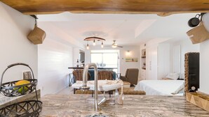 A modern kitchen with a granite countertop, a stainless steel sink, and a hanging pot rack. - Stunning Ocean Views STEPS from the Beach with Pool! Fabulous 4th Floor Studio! (New Smyrna Beach)