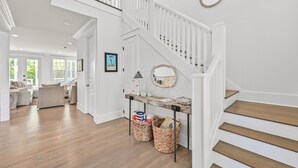 A spacious living area with a wooden staircase, a white railing, and a view of the outdoors. - 4 Bedroom Gorgeous Beachy Home - Resort Pool - 6 Seater Golf Cart (Santa Rosa Beach)