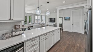 A modern kitchen with white cabinetry, a large island, pendant lights, and a built-in oven. - 4 Bedroom Gorgeous Beachy Home - Resort Pool - 6 Seater Golf Cart (Santa Rosa Beach)