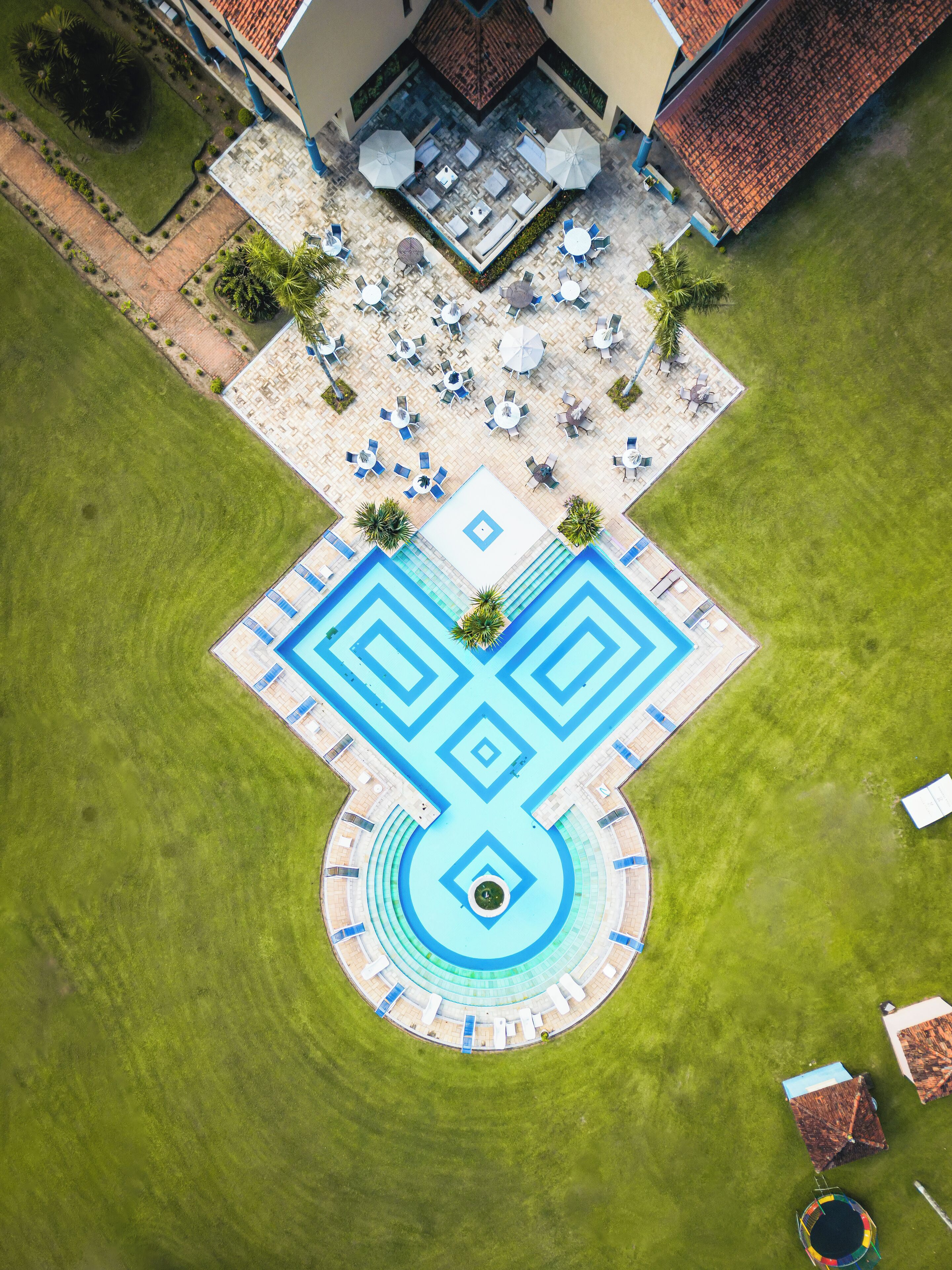 An aerial view of a courtyard with a geometric pool design, outdoor seating, and a small pool area.