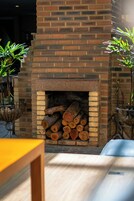 Una chimenea de ladrillo con leña apilada, rodeada de macetas con plantas.