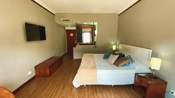 A hotel room with a bed, bedside table, lamp, and a television on the wall.
