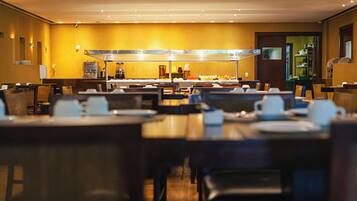 A hotel dining area with multiple tables and chairs, a buffet counter, and a coffee station.