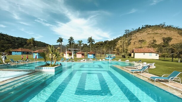 Une grande piscine à l’eau d’un bleu cristallin, entourée de chaises longues et de palmiers.