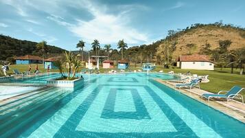 Una piscina al aire libre, sombrillas, sillones reclinables de piscina