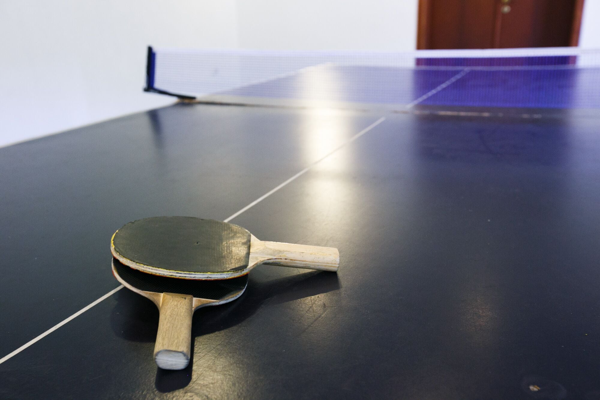 A table tennis table with a paddle in the foreground.