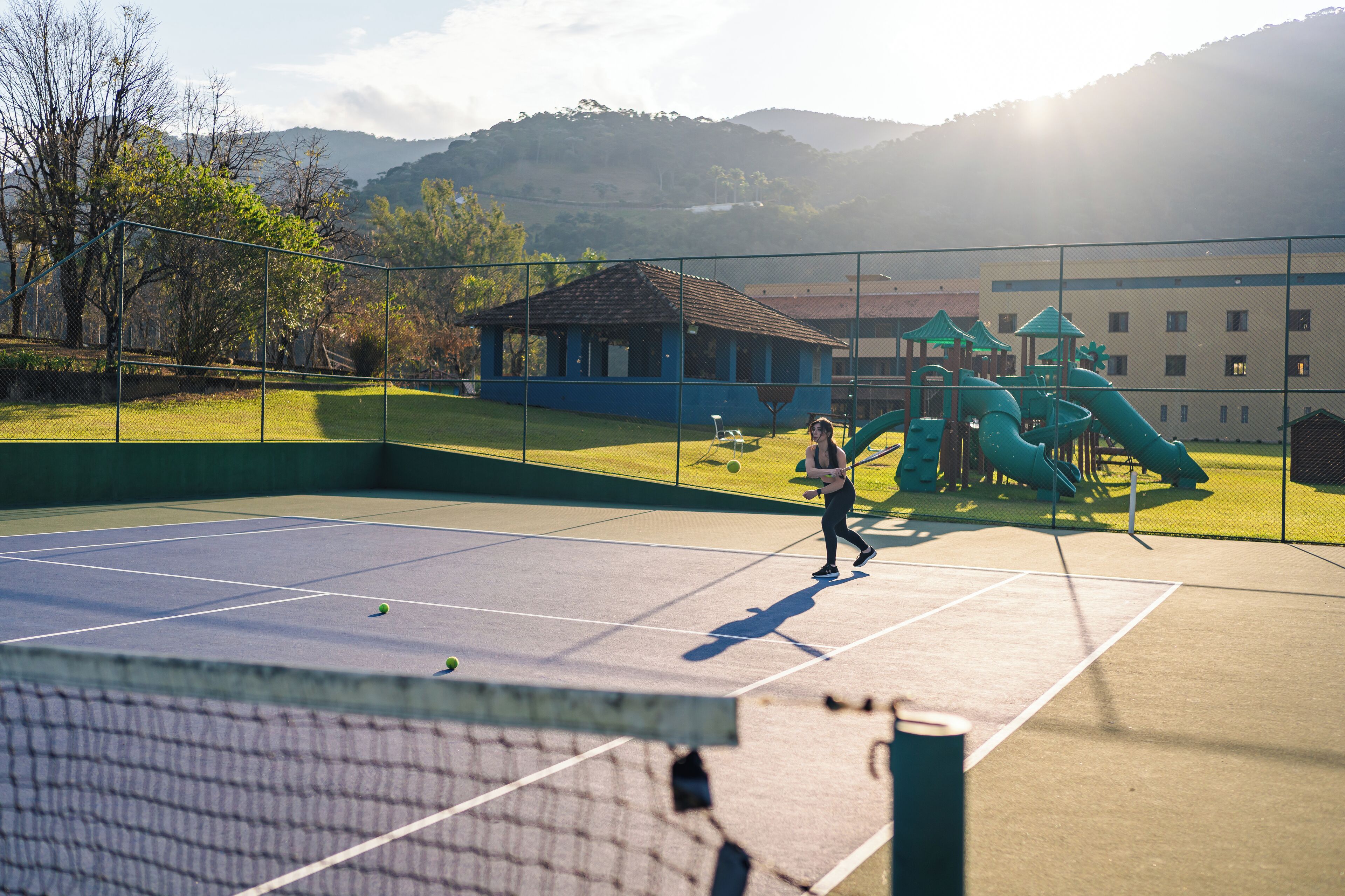 Una cancha de tenis con una red, rodeada por una valla.