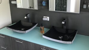 A bathroom with two black vessel sinks, a mirror above each sink, and a dark wooden vanity with drawers. - Beautifully remodeled  “Over the water” Townhouse suite! (Berry Islands)