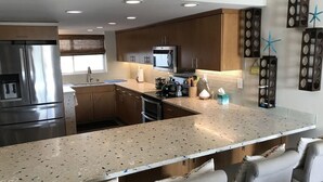 A modern kitchen with a large island, stainless steel appliances, and wooden cabinets. - Beautifully remodeled  “Over the water” Townhouse suite! (Berry Islands)