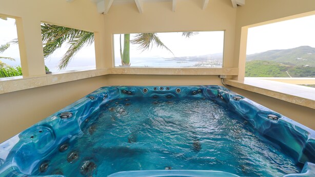 A hot tub with a view of the ocean and hills.