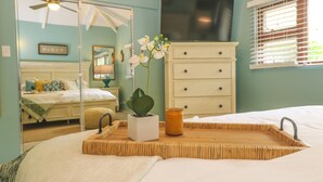 A bedroom with a bed, bedside table, dresser, and a window with blinds.