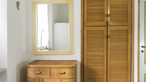 A room with a wooden wardrobe, a mirror with a yellow frame, and a wicker dresser. - M297 - Marcelli, three-room apartment with garden at 100 m. from the sea (Marcelli)
