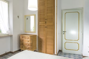 Un dormitorio con una cama, un aparador de madera, un armario, un espejo y una puerta con marco dorado.
