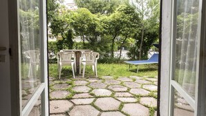 An open door leading to a patio with hexagonal stone tiles, two white plastic chairs, and a blue table. - M297 - Marcelli, three-room apartment with garden at 100 m. from the sea (Marcelli)