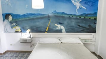 Una camera da letto con un letto, un comodino, una lampada e un affresco sulla parete.