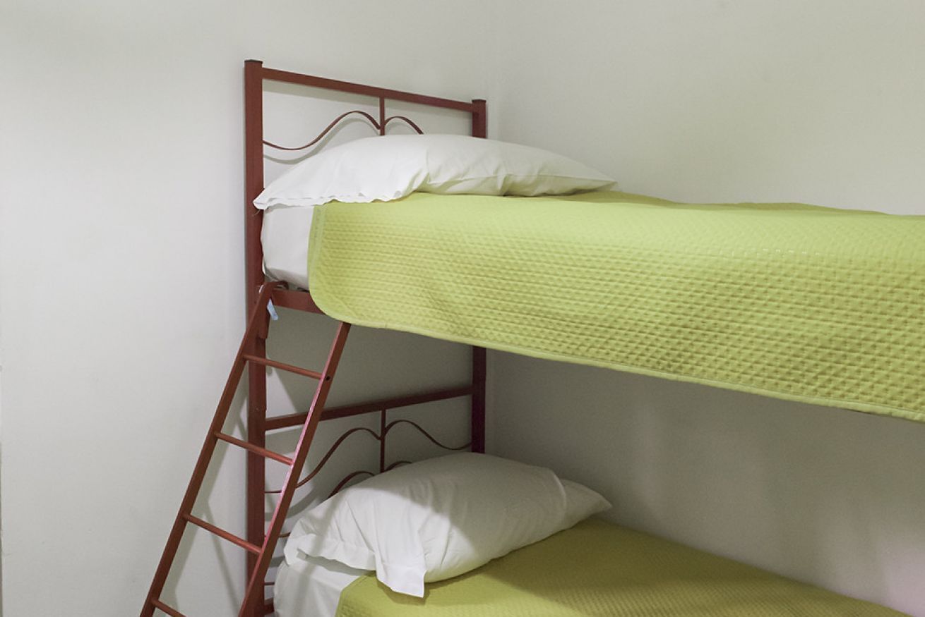 Un letto a castello con una scaletta, cuscini bianchi e una coperta verde.