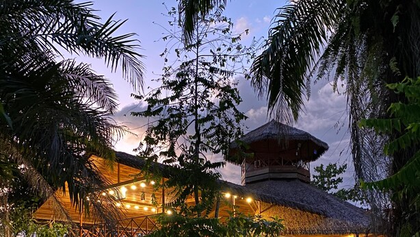 A resort with a thatched-roof structure, a stone pathway, and lush greenery. - Corcovado Private Villas (Puerto Jiménez)