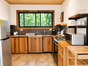 A kitchen with wooden cabinets, a window with a view of greenery, a stove, and a microwave.
