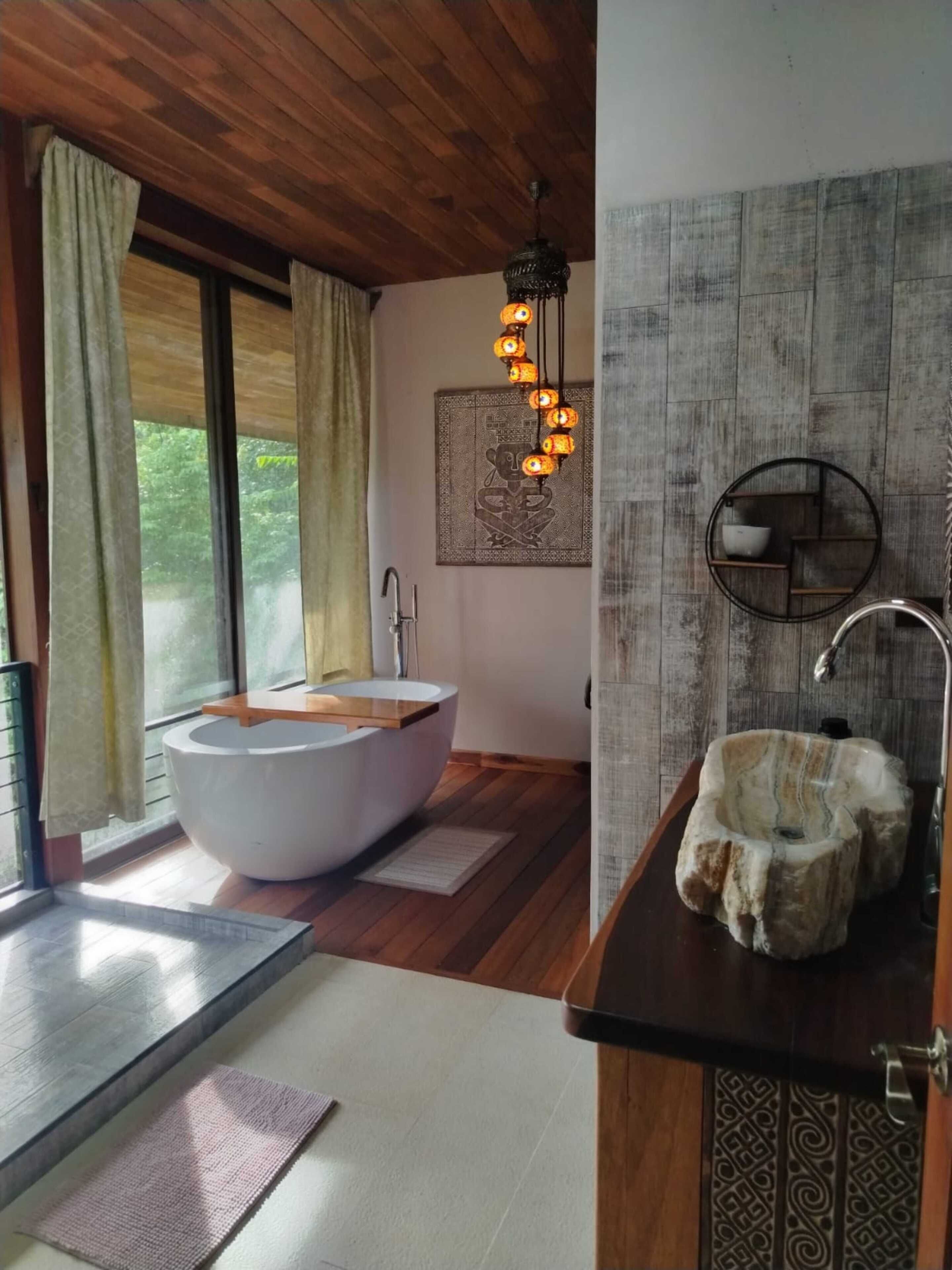 Un baño moderno con una bañera independiente, un lavabo redondo y un aplique de techo.