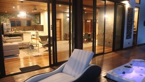 A modern living room with a glass door leading to a dining area, a hot tub, and a kitchen visible through the glass. - Corcovado Private Villas (Puerto Jiménez)