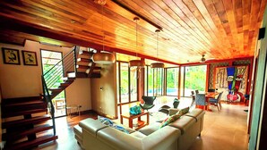 A modern living room with a staircase, a sofa set, and a dining area. - Corcovado Private Villas (Puerto Jiménez)
