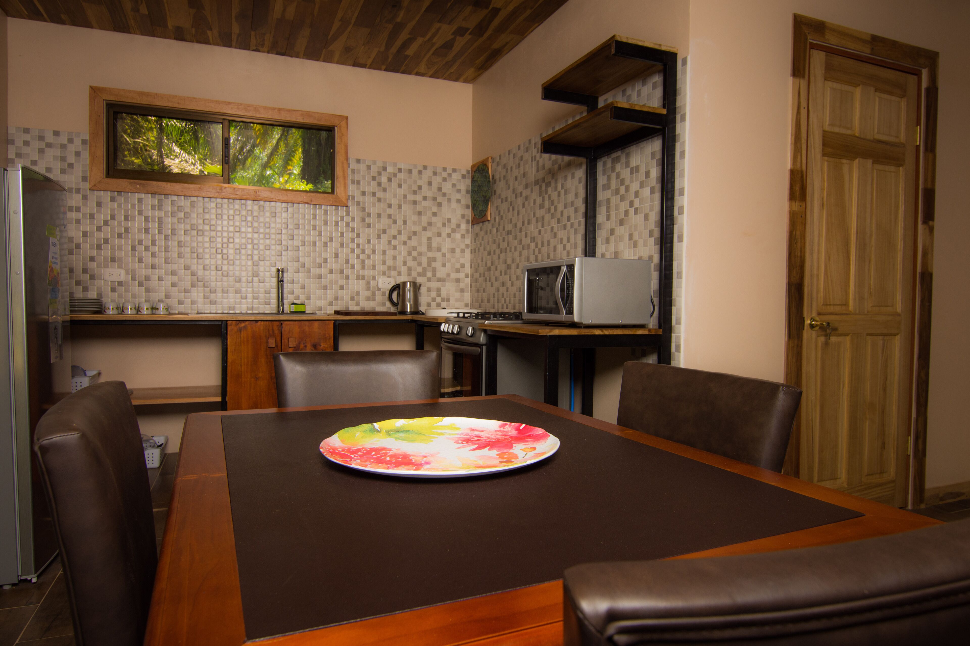 A dining area with a table, chairs, a microwave, and a stove in the background.