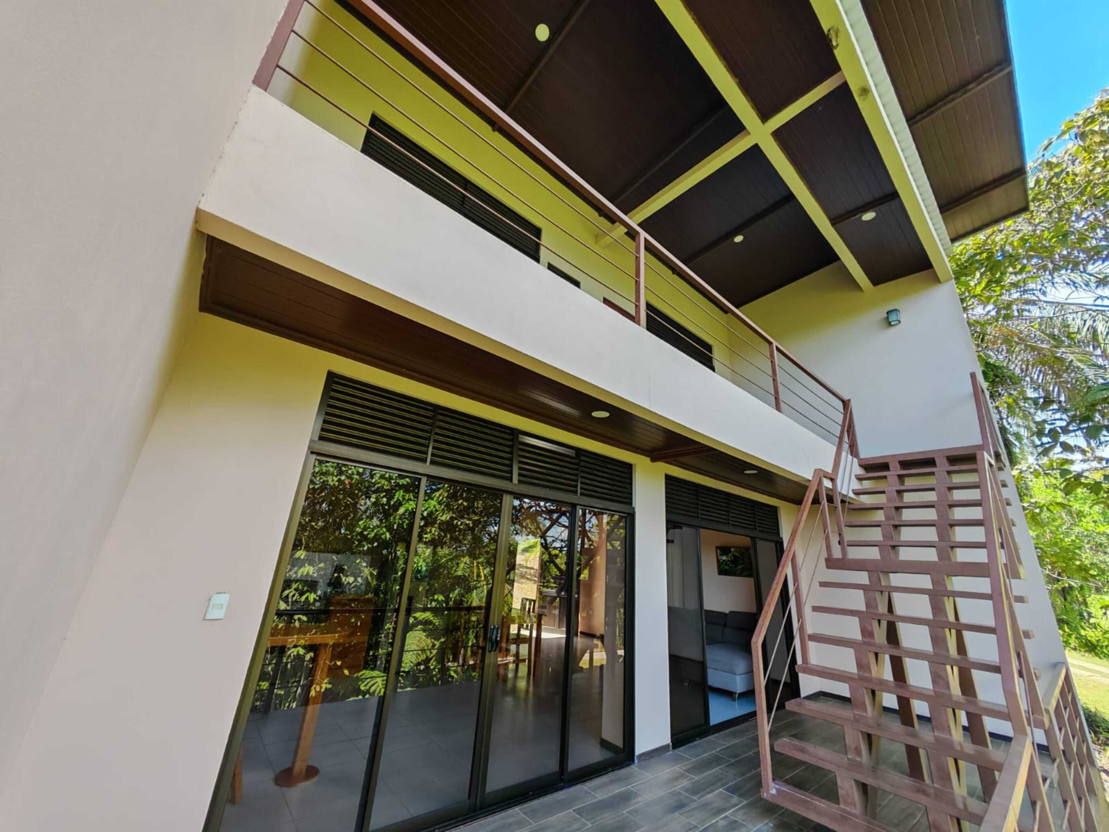 A modern two-story building with a glass entrance, a wooden staircase, and a balcony.