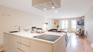 A modern kitchen with a central island, a dining area with a table and chairs, and a living space with a sofa and a TV.
