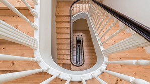 A spiral staircase with white balusters and a wooden finish, leading to an upper floor.