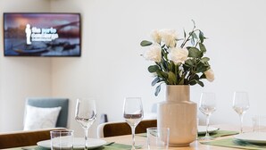 A dining table set with plates, glasses, and a vase of flowers.