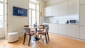 Una cocina moderna con armarios blancos, microondas y un comedor con mesa redonda y sillas.