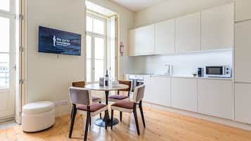 Una cucina moderna con mobili bianchi, un forno a microonde e un'area pranzo con un tavolo rotondo e sedie.