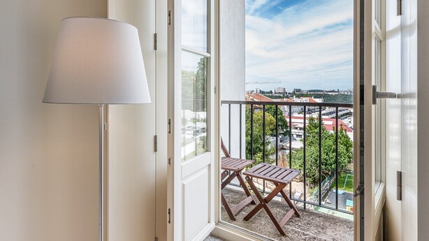 A balcony with a view of a cityscape, a wooden table, and a floor lamp. - GuestReady - La Maison Aires Gouveia 5 (Porto)