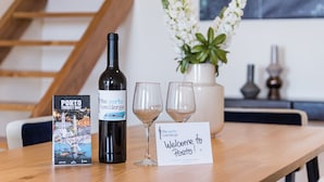 Una mesa con una botella de vino, dos copas de vino, un cartel de bienvenida, un mapa turístico y un jarrón con flores.