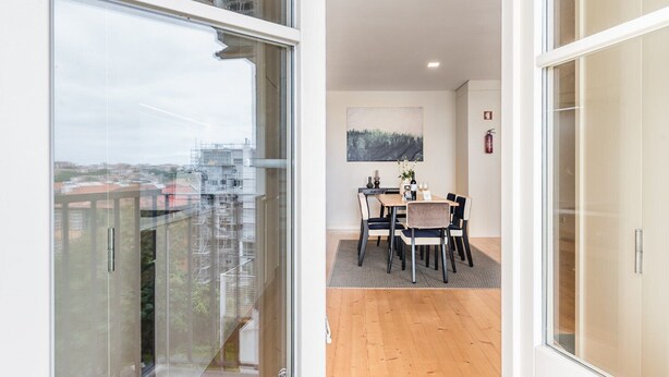 Un apartamento moderno con balcón, una zona de comedor con mesa y sillas, y vistas a la ciudad.