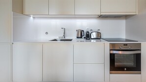 A modern kitchen with a stainless steel sink, kettle, toaster, and oven. - GuestReady - La Maison Aires Gouveia #8 (Porto)