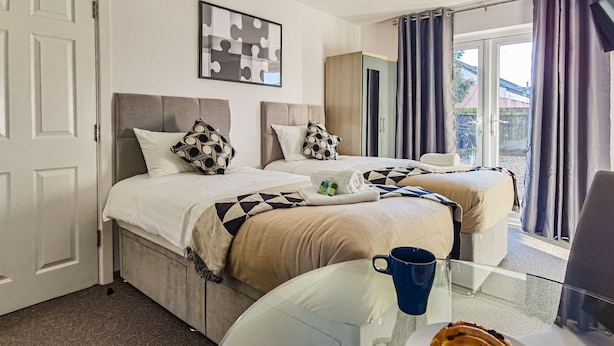 Een hotelkamer met twee bedden, een glazen tafel met een bord eten en uitzicht op buiten.