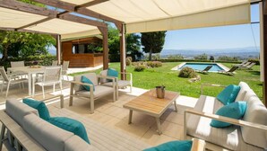 Un patio al aire libre con una mesa de madera, un sofá blanco y sillas.