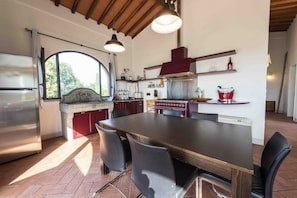 A kitchen with a large island, modern appliances, and a view through a window. - Casina al Vento by MMega (Malafrasca-San Frustino)