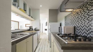 Una cocina estrecha con una isla central, un refrigerador y un microondas.