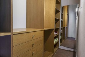 Un dressing avec des tiroirs et des étagères en bois, une porte de placard miroir et un sol carrelé.