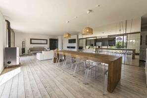 Een moderne keuken met een houten kookeiland, transparante stoelen en hanglampen.