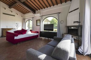 Ein geräumiges Wohnzimmer mit einem roten Sofa, einem grauen Sofa und einem Kamin.