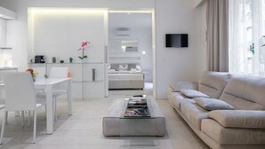 Una sala de estar moderna con un sofá, una mesa de centro, un televisor y un comedor con sillas y una mesa.