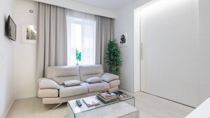 Una sala moderna con un sofá, una mesa de centro de vidrio, una planta y una puerta.